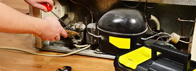 Refrigerator repair technician fixing the compressor and wiring in Westminster, CO