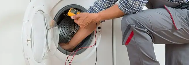 Dryer repair technician inspecting and repairing a clothes dryer in Denver, CO