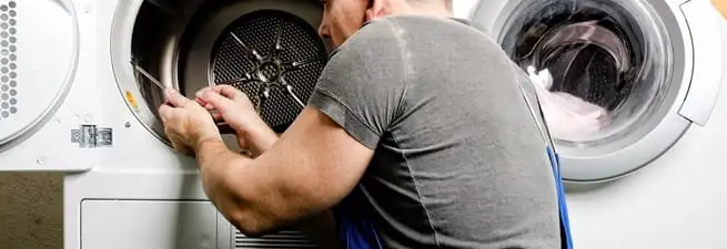 Dryer repair technician fixing a clothes dryer drum in Denver, CO
