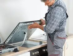 Appliance repair technician installing a built-in cooktop in Denver, CO
