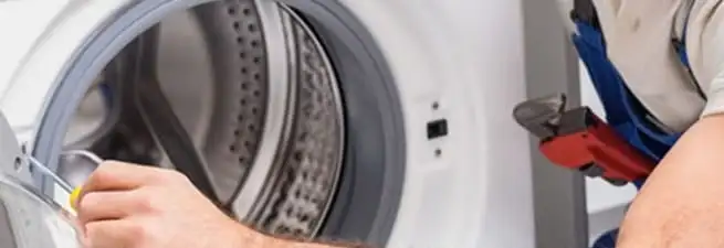 Appliance technician repairing a clothes dryer drum and internal parts in Denver, CO