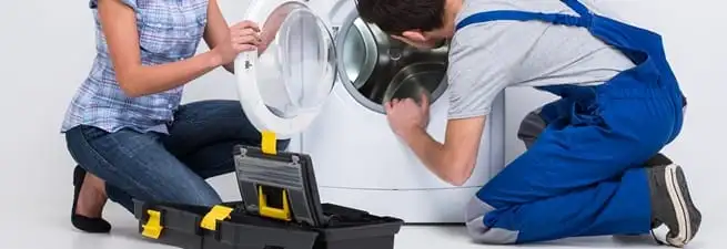 Washer repair technician inspecting a front-load washing machine with tools in Denver, CO