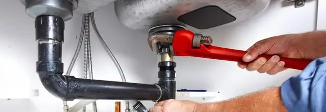 Garbage disposal repair technician tightening the sink drain and disposal connection in Denver, CO