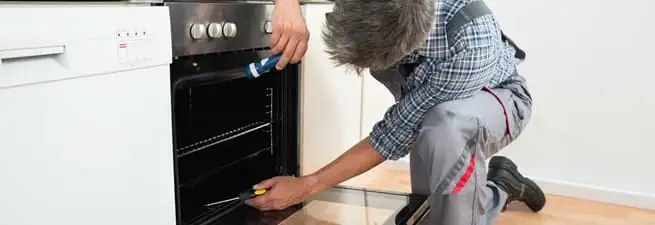 Oven repair technician inspecting and servicing an electric oven in Denver, CO