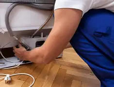Appliance repair technician fixing refrigerator water line and connections in Denver, CO