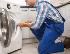 Washing machine repair technician servicing a front-load washer in Denver, CO
