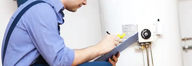 Water heater repair technician inspecting the unit and recording service notes in Denver, CO