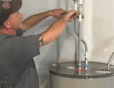 Water heater repair technician tightening supply line connections in Denver, CO